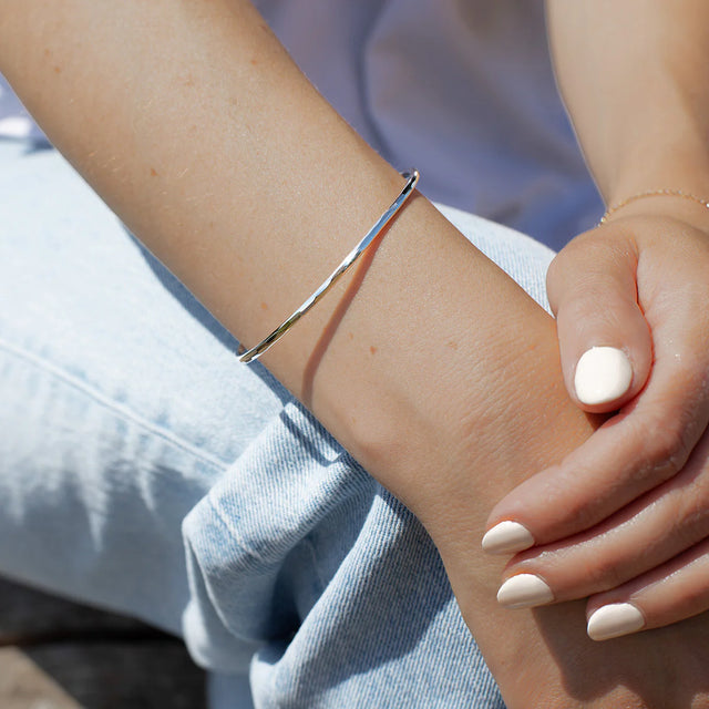 Silver bracelet on a wrist with a blurred background