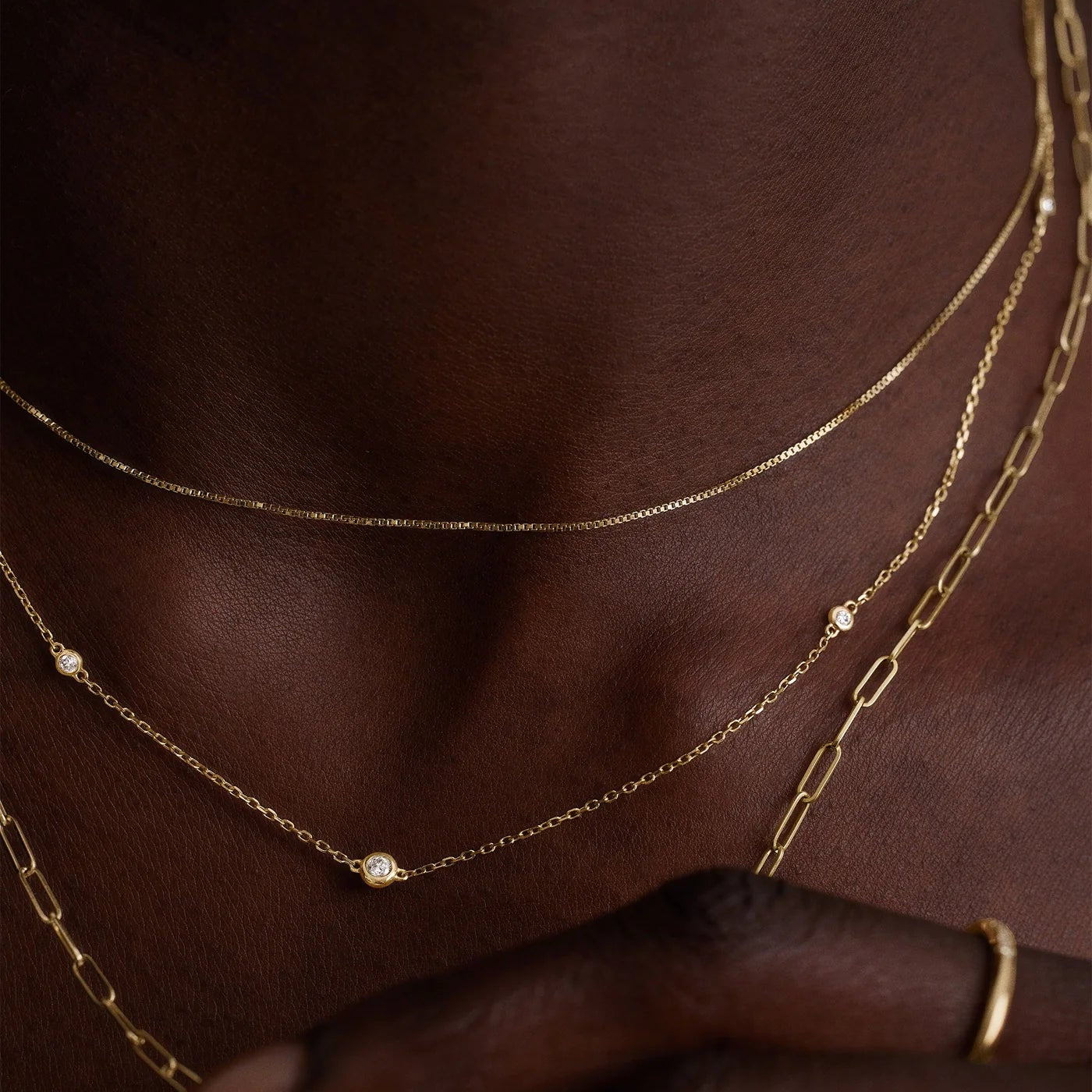 Gold necklaces on a person's neck with a blurred background