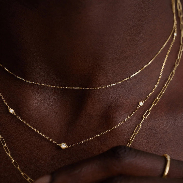 Gold necklaces on a person's neck with a blurred background
