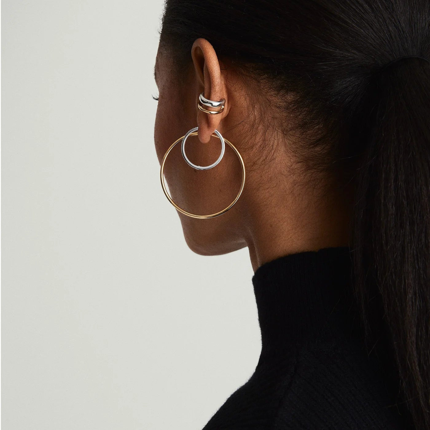Person wearing gold hoop earrings on a plain background