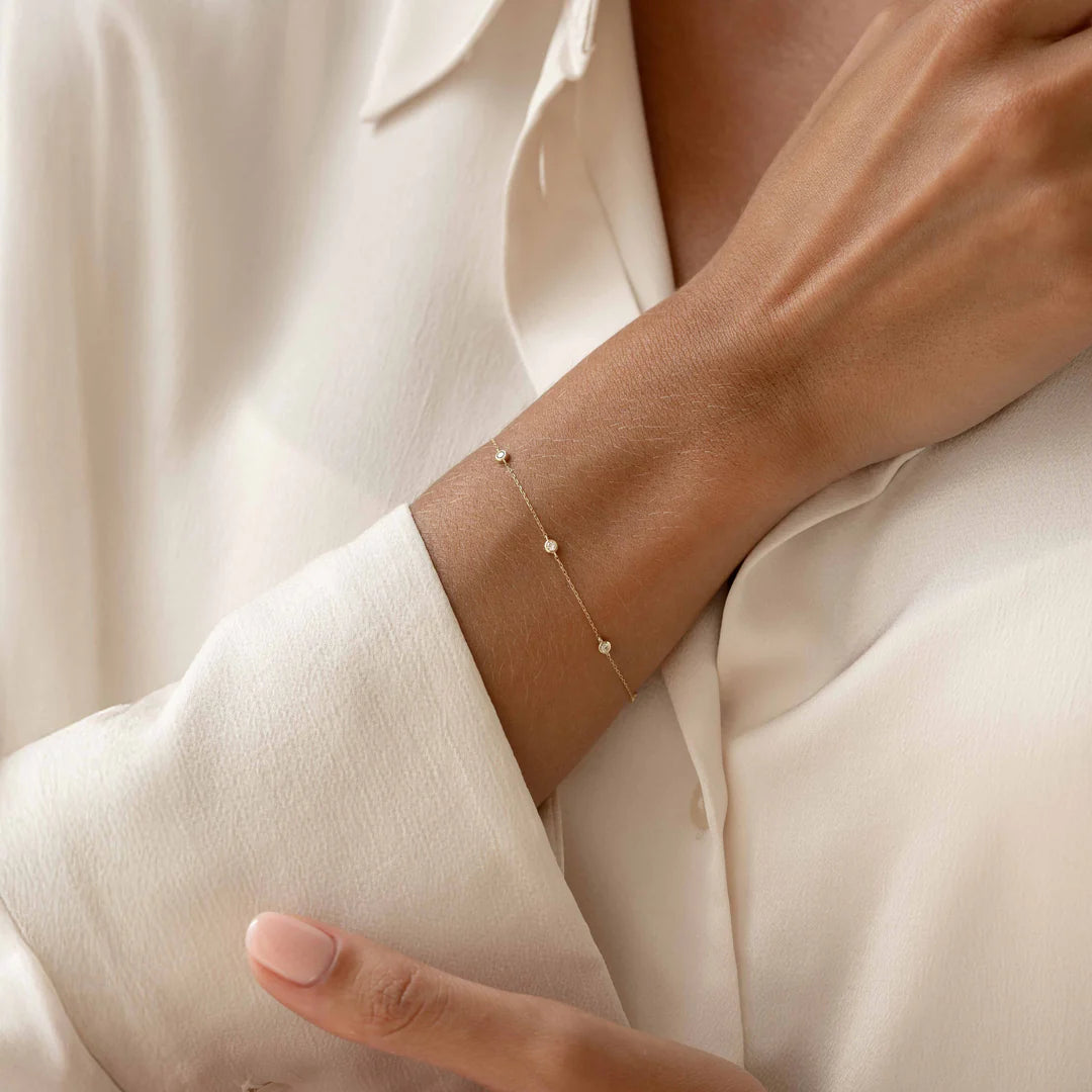 Gold bracelet on a wrist with a white shirt background