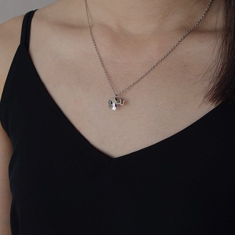 Necklace with a small pendant worn by a person against a neutral background