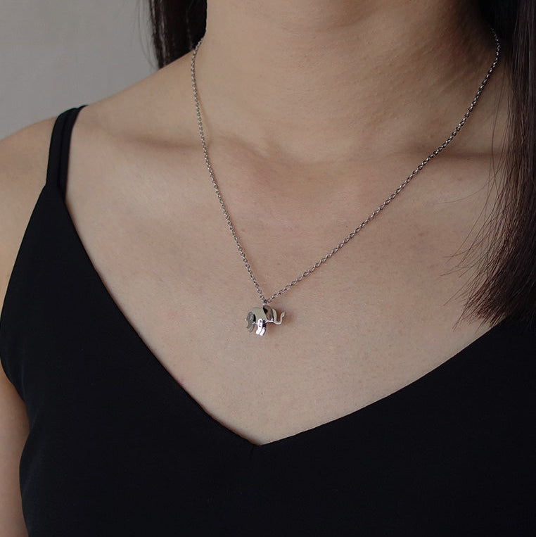 Necklace with a small pendant worn by a person against a neutral background