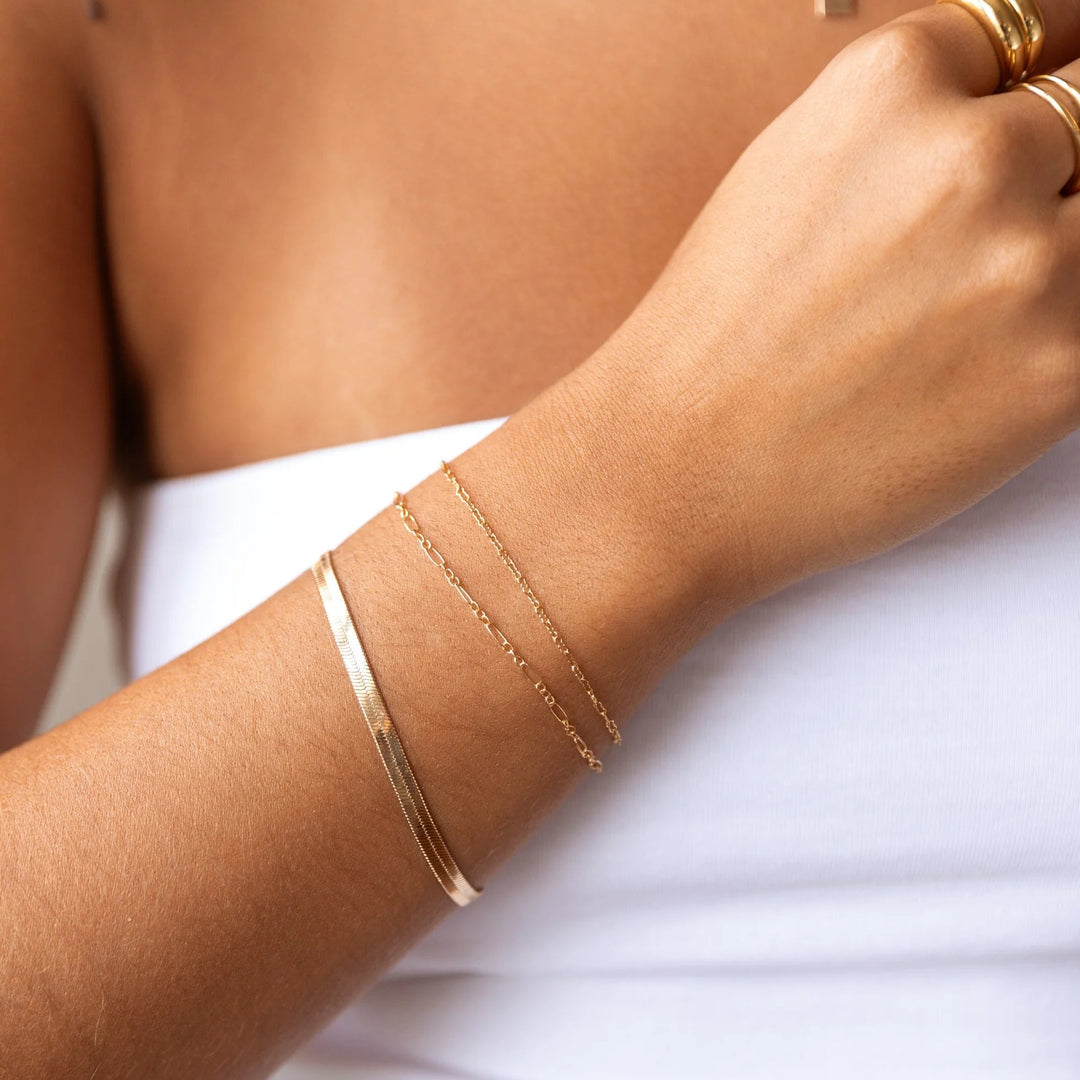 Gold bracelet on a wrist with a neutral background