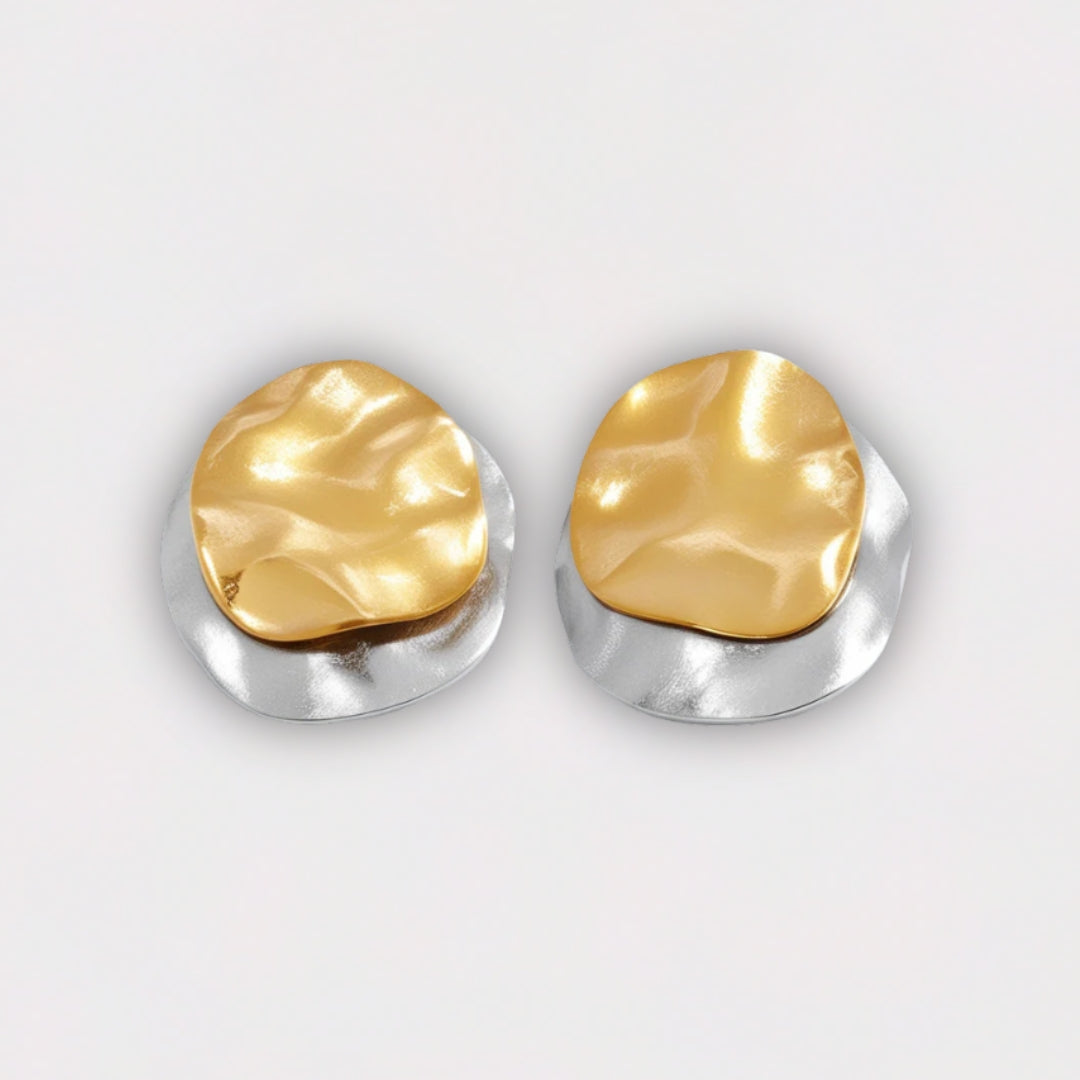 Pair of gold and silver earrings on a light gray background