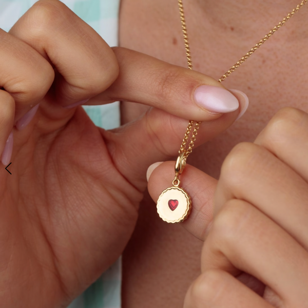 Gold necklace with a heart pendant held by hands