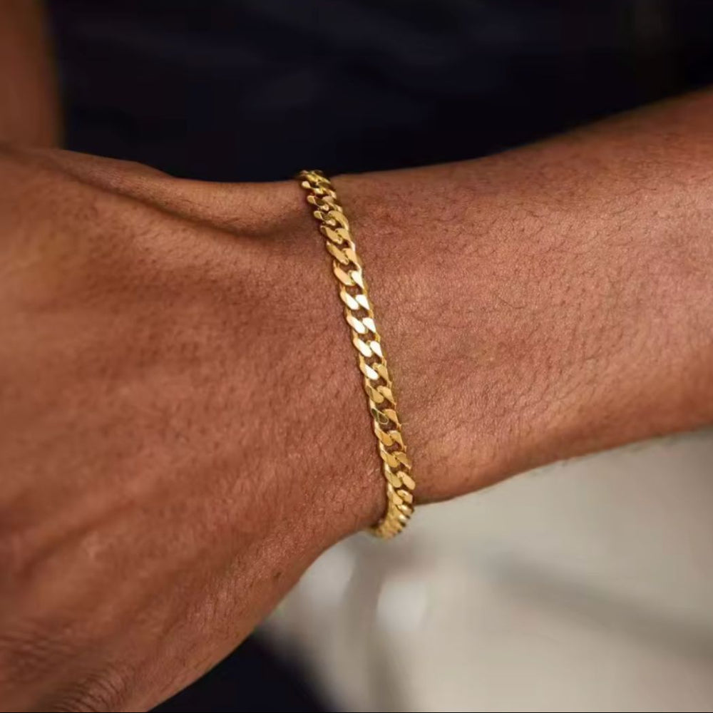 Gold chain bracelet on a wrist with a blurred background