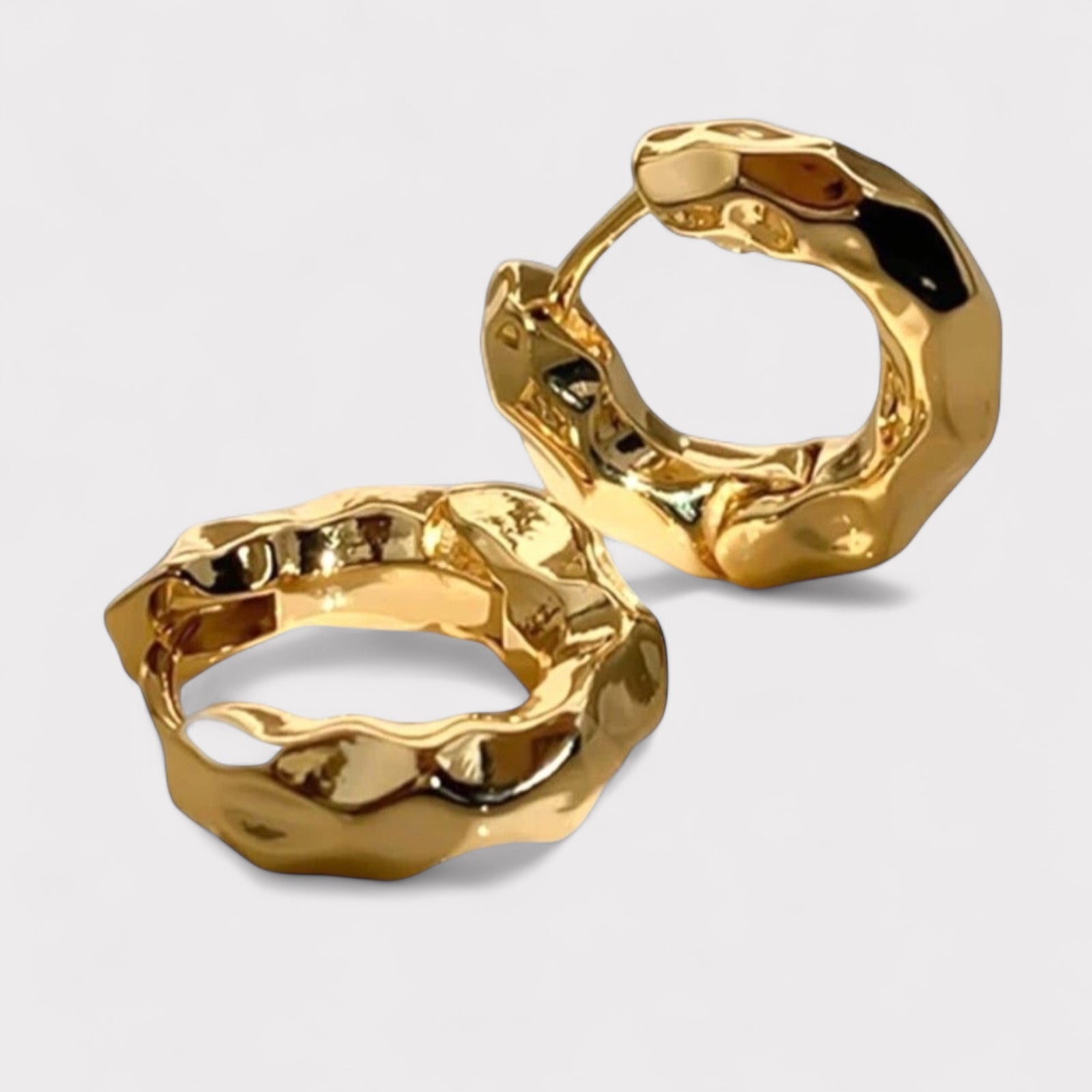 The Molten Huggie Hoops from LUCID are small, chunky sculptural hoops in recycled gold or silver with a wavy design, shown on a plain light background.