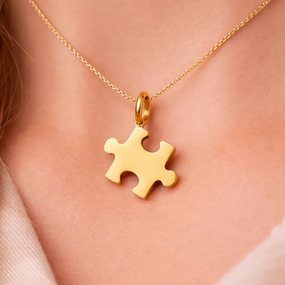 Gold puzzle piece pendant necklace on a person's neck