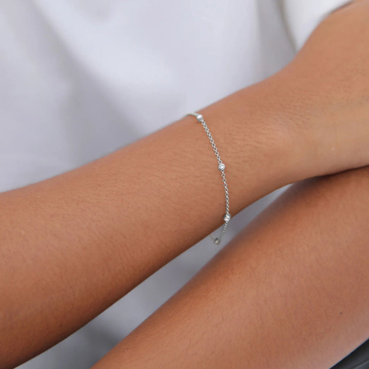 Silver bracelet on a person's wrist against a neutral background
