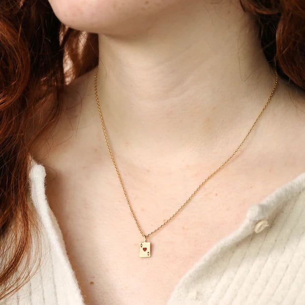Gold necklace with a small pendant worn by a person with red hair.