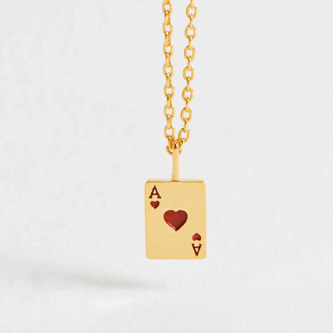 Gold necklace with an ace of hearts pendant on a light gray background