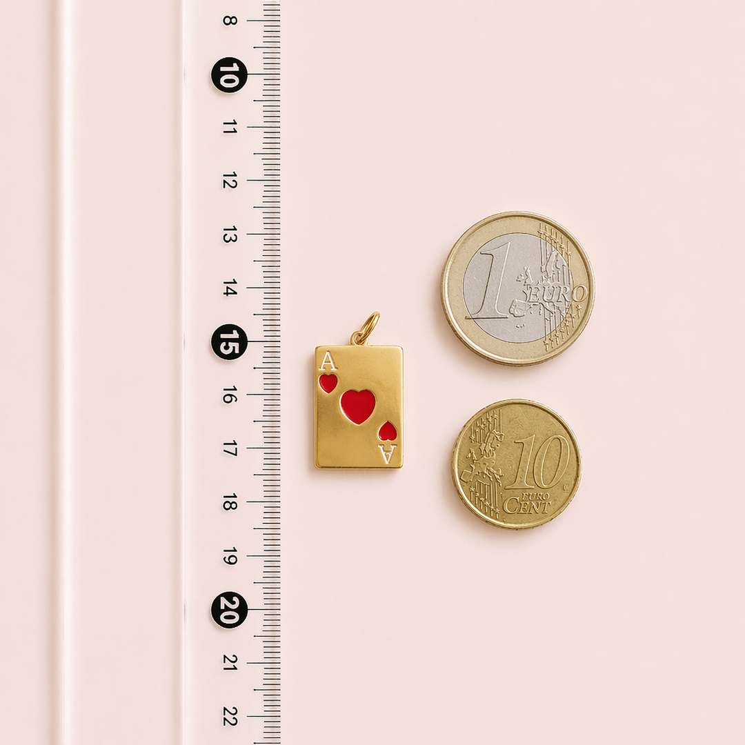 Gold card charm and two coins on a pink surface with a ruler for scale.