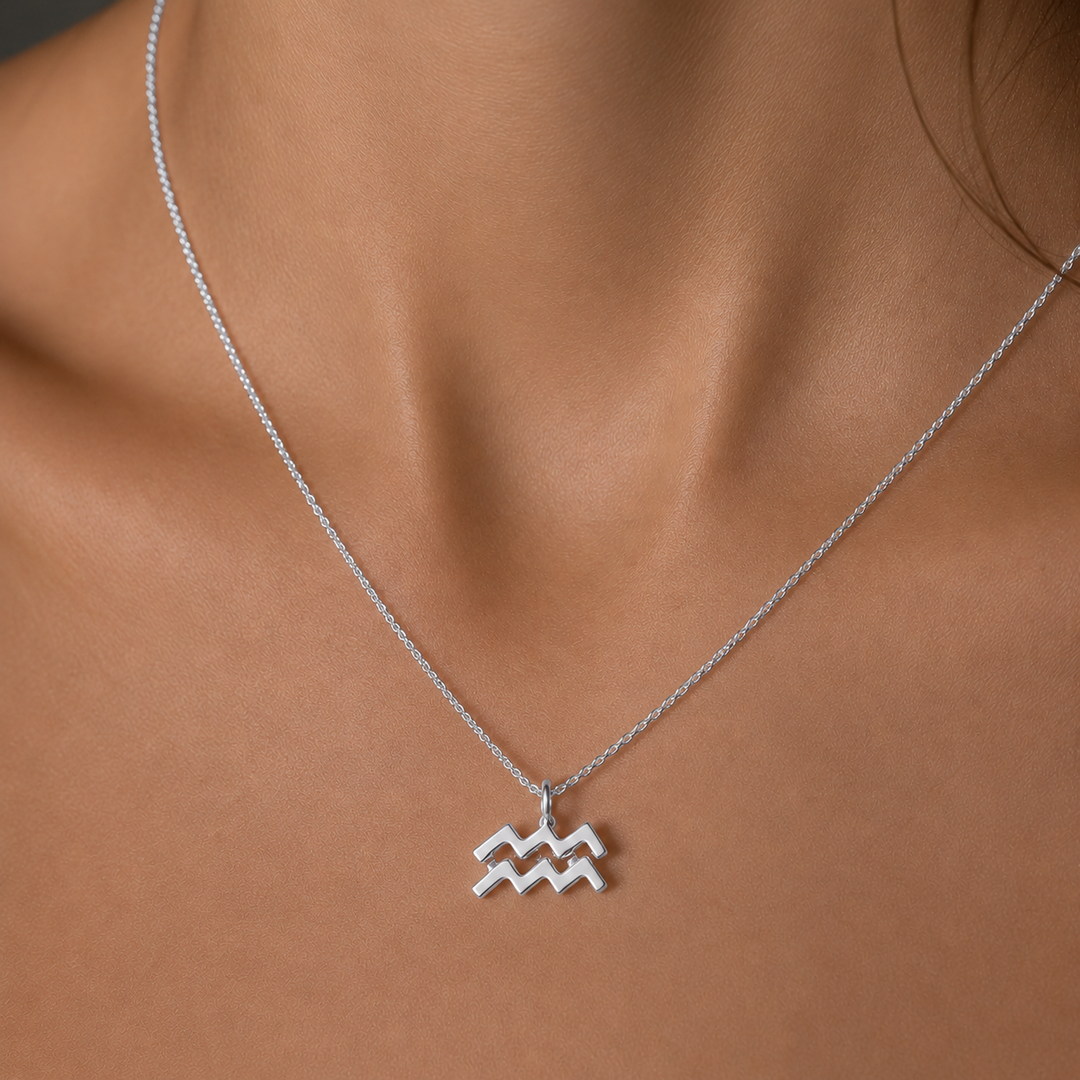 Silver Aquarius zodiac necklace on a person's neck against a neutral background