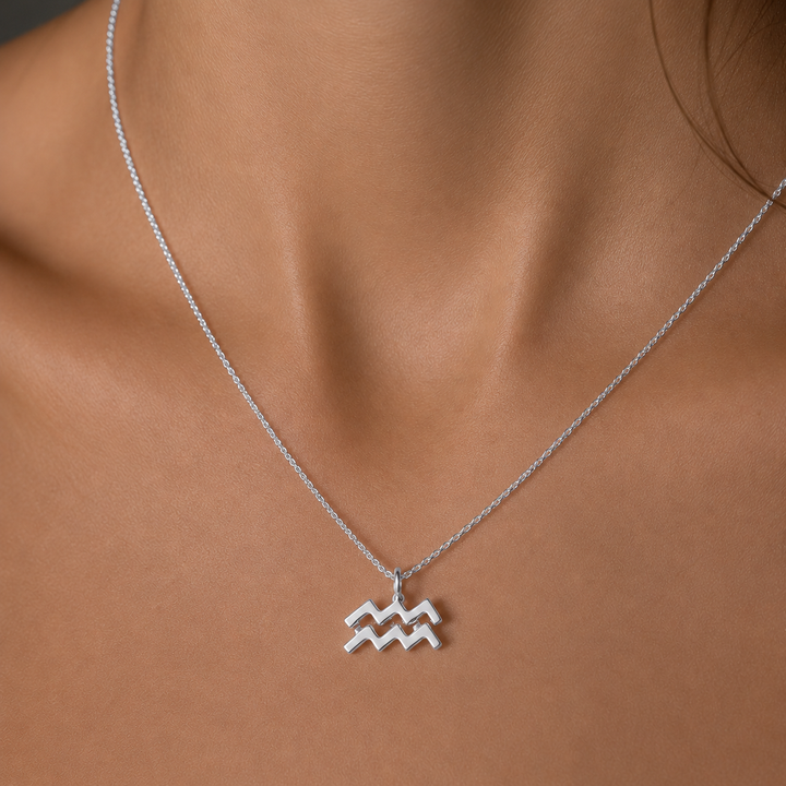 Silver Aquarius zodiac necklace on a person's neck against a neutral background