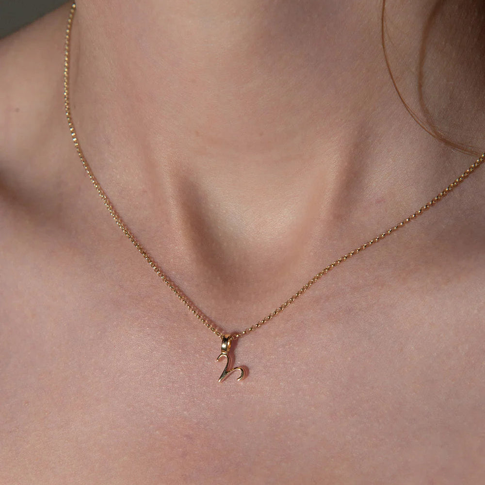 Rose gold necklace with a small pendant on a person's neck