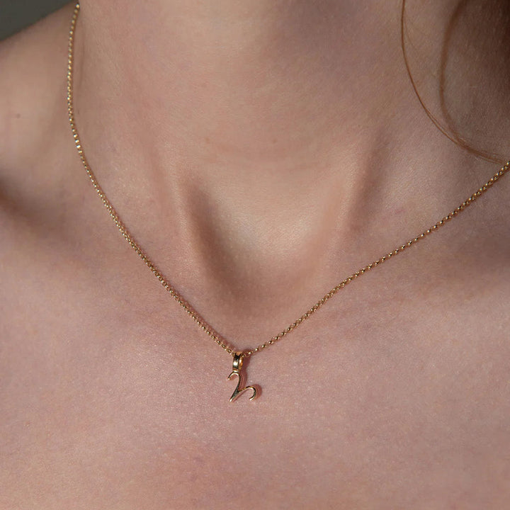 Rose gold necklace with a small pendant on a person's neck