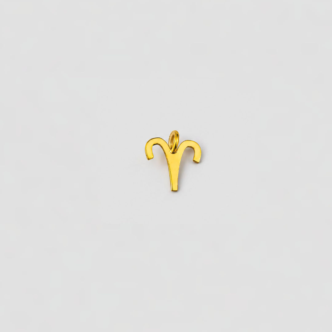 Gold Aries zodiac sign pendant on a light gray background