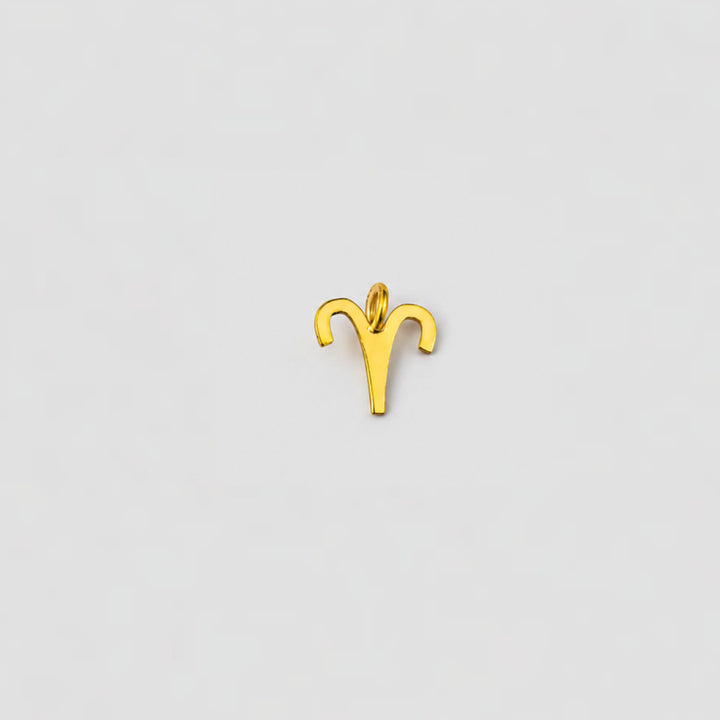 Gold Aries zodiac sign pendant on a light gray background