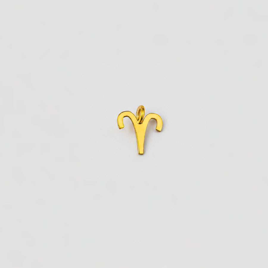 Gold Aries zodiac sign pendant on a light gray background
