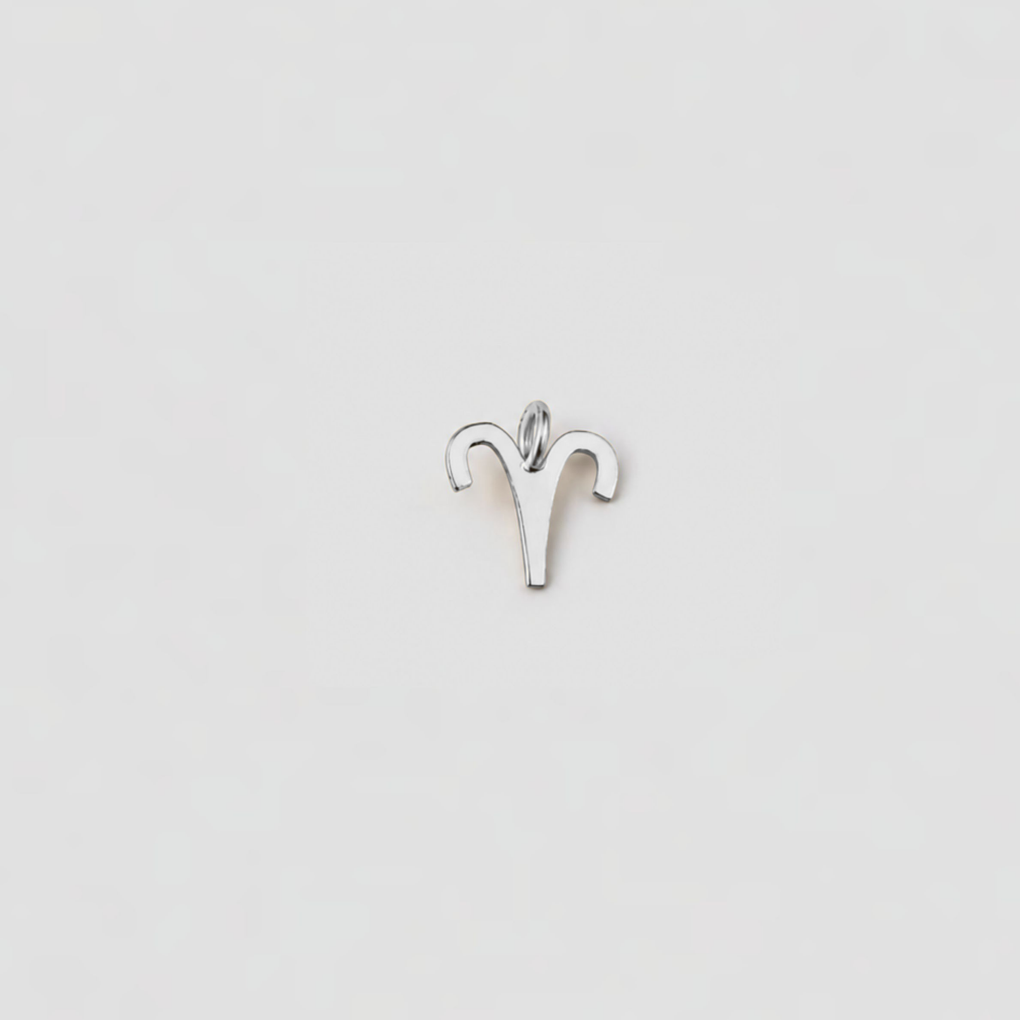 Silver Aries zodiac sign pendant on a light gray background