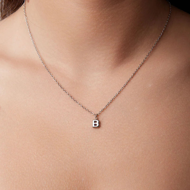 Necklace with a 'B' pendant on a person's neck