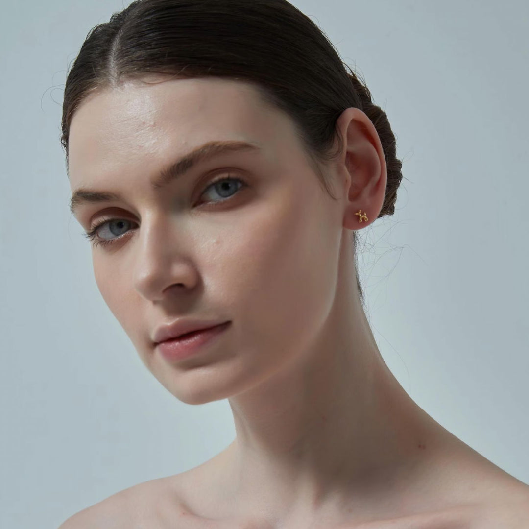 Close-up of a person wearing a gold earring against a plain background