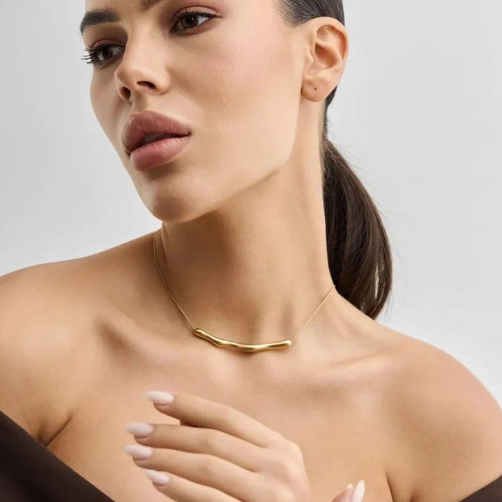 Woman wearing a gold necklace against a neutral background