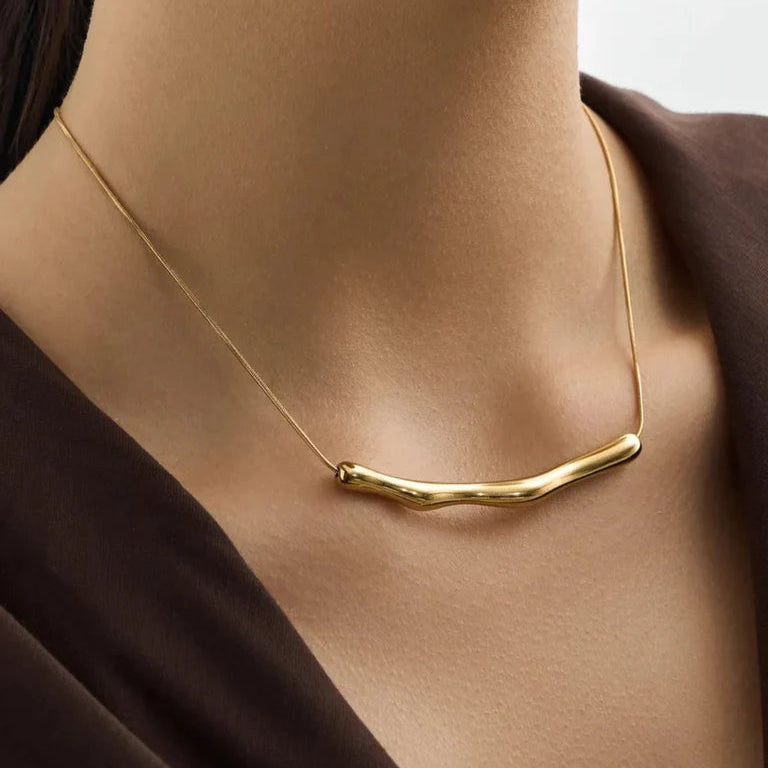 Gold necklace on a person wearing a dark brown garment