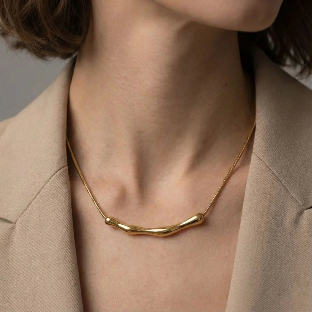 Gold necklace worn by a person with a neutral background