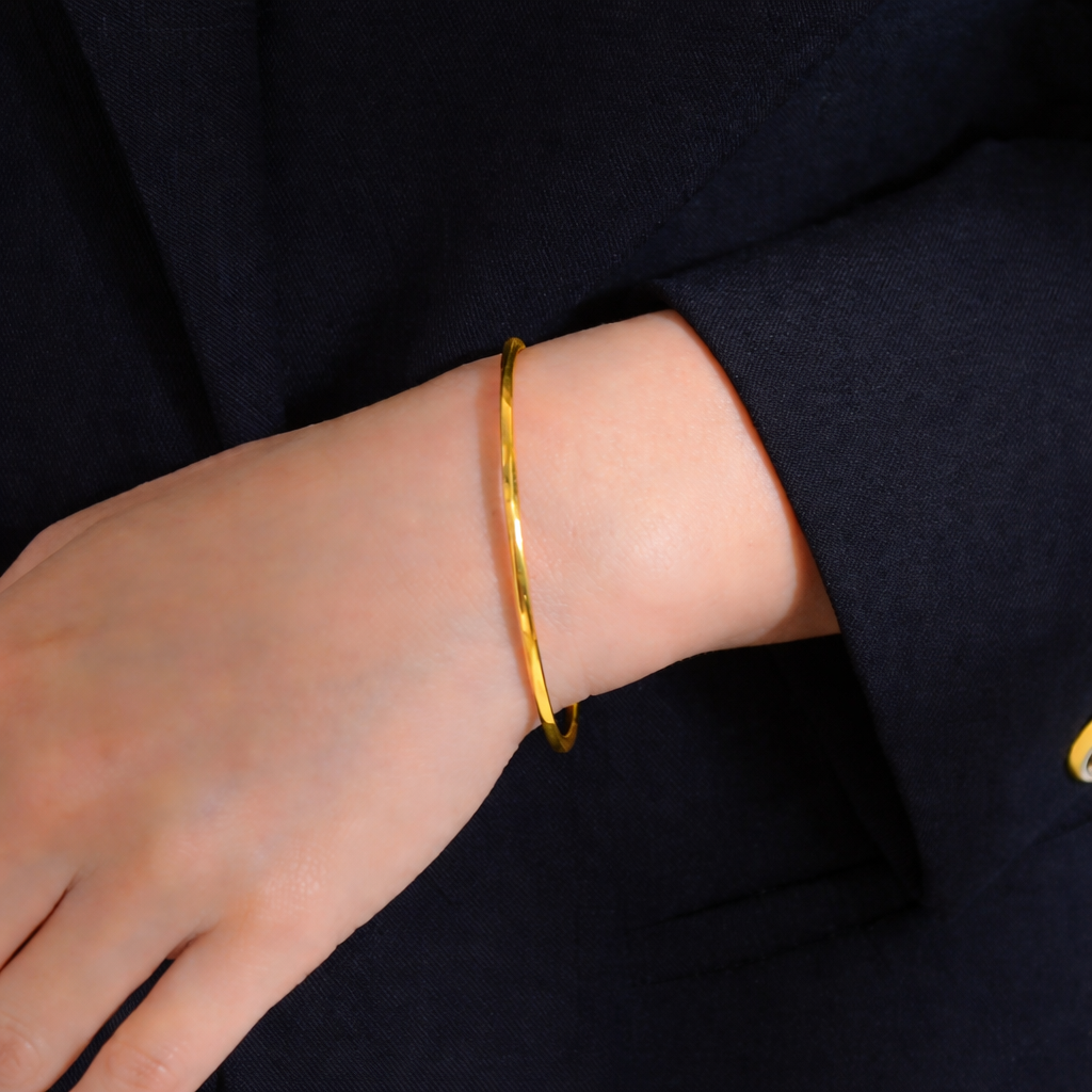 Gold bracelet on a person's wrist against a dark background