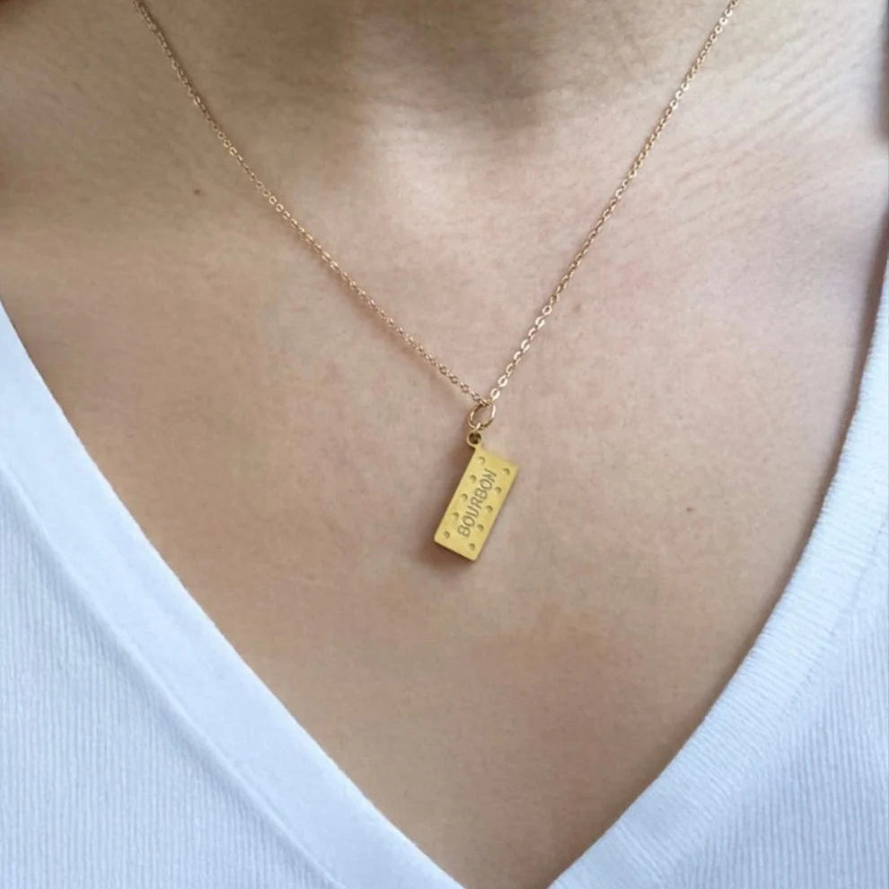 Gold necklace with a pendant on a person wearing a white top