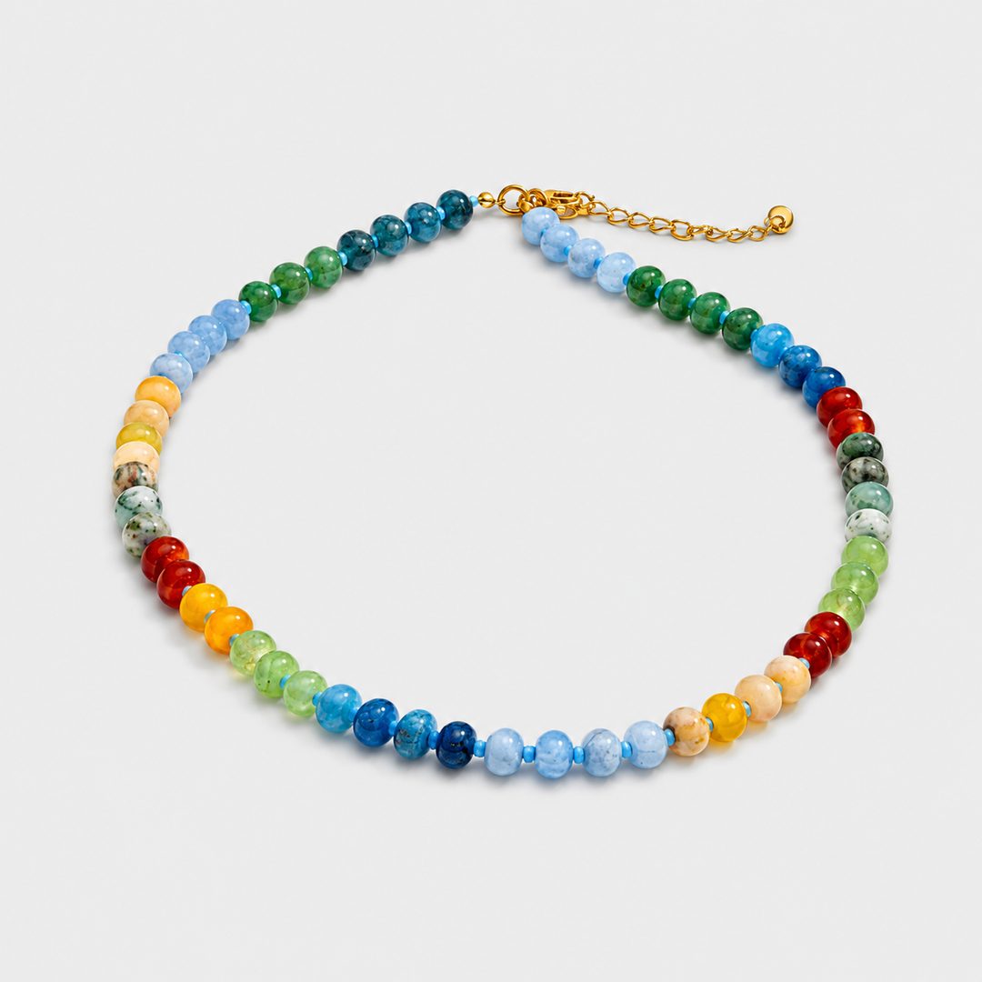 Multicolored beaded necklace with a gold chain on a light gray background
