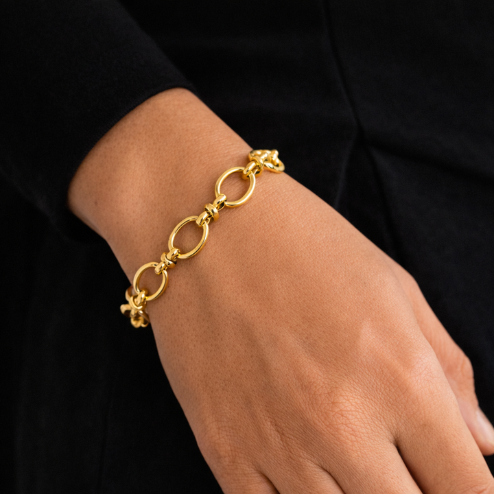 Gold bracelet on a person's wrist against a black background