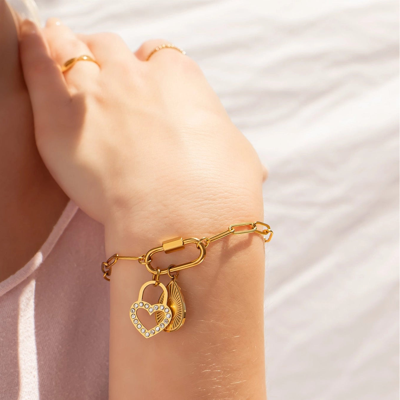 Gold bracelet with heart-shaped charms on a person's wrist against a light background