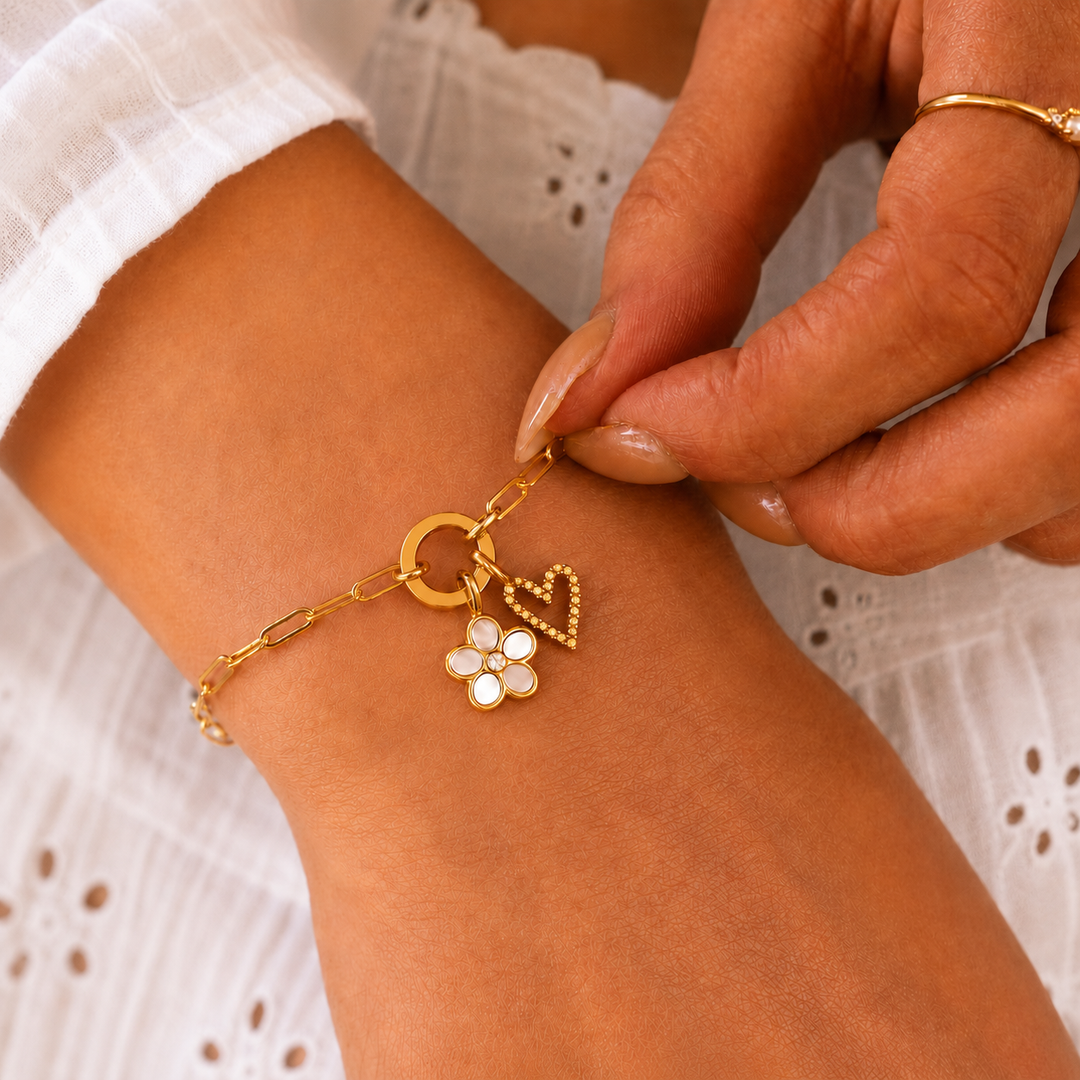 Gold bracelet with charms being adjusted on a wrist