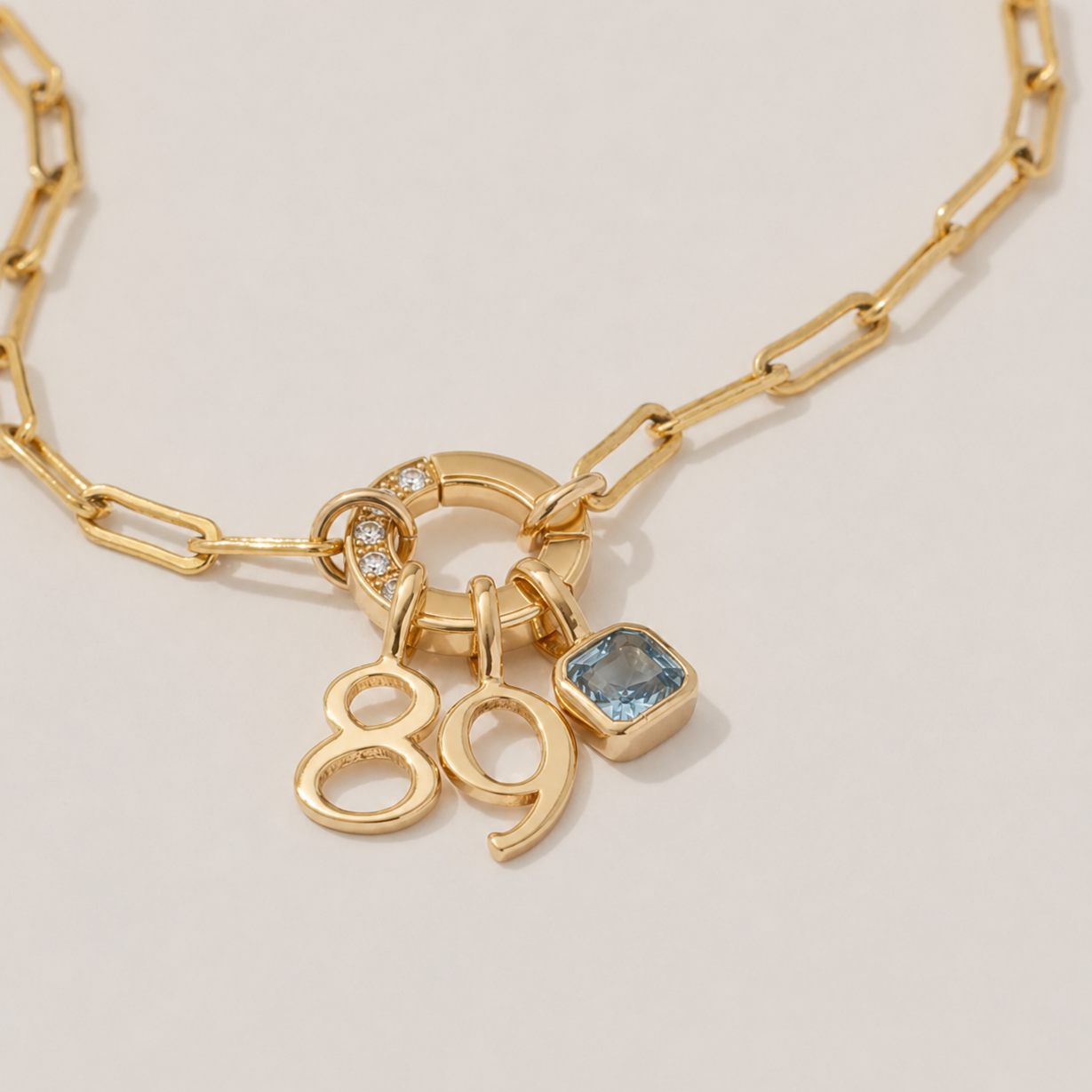 Gold necklace with number and gemstone charms on a light background