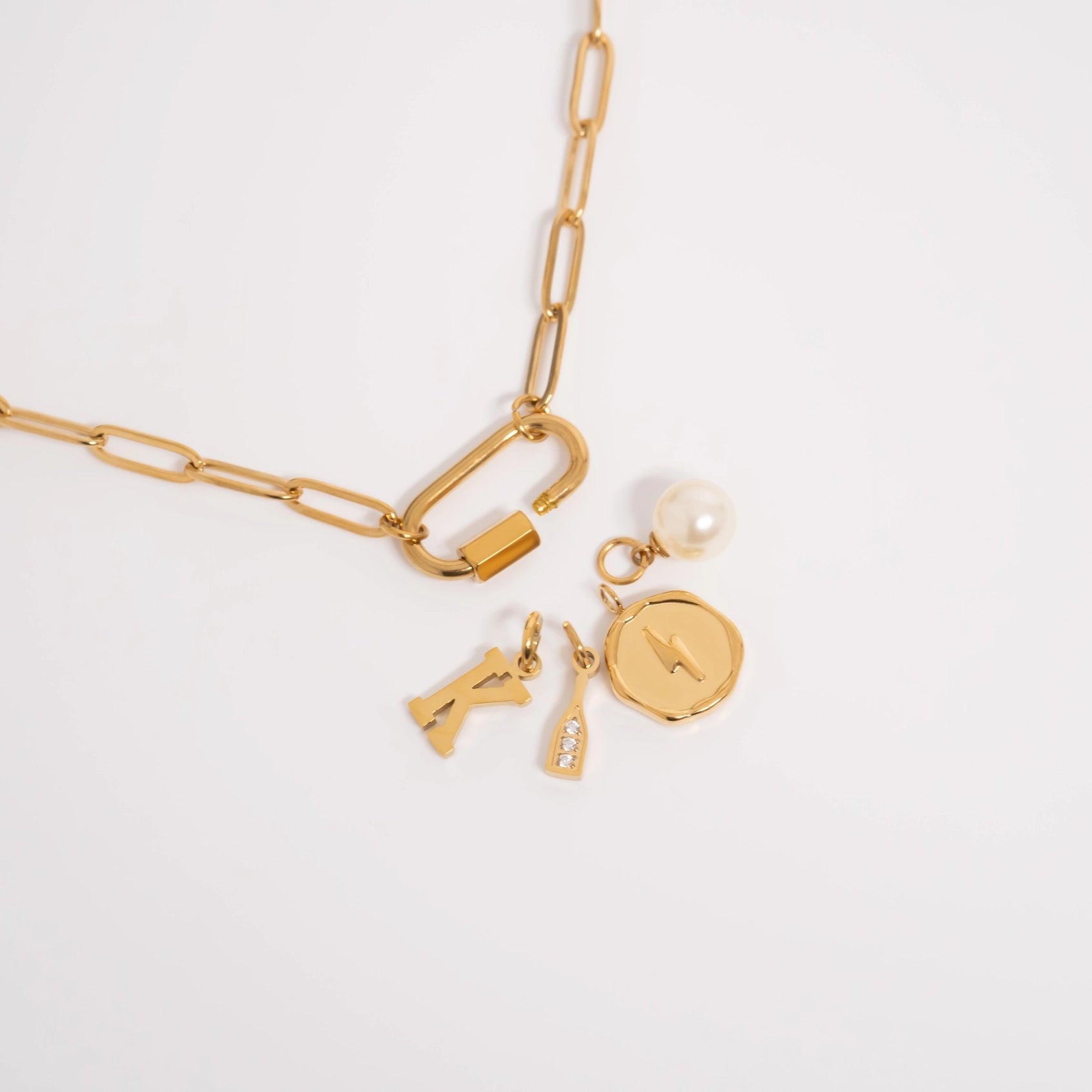 Gold chain necklace with charms on a light gray background