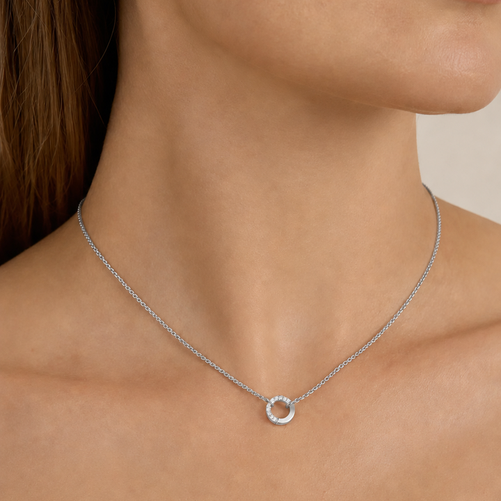 Silver necklace with a small round pendant on a person's neck