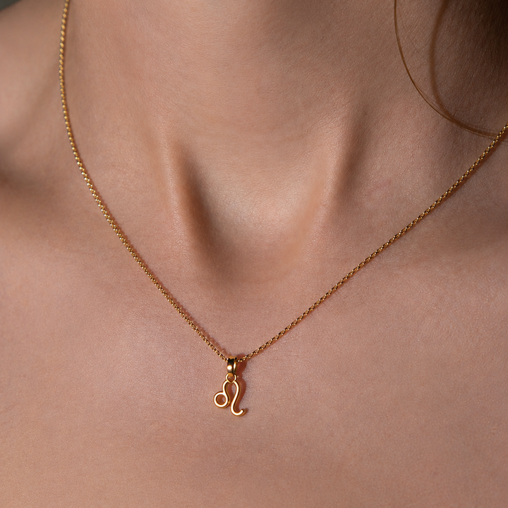 Gold necklace with a 'L' pendant on a person's neck
