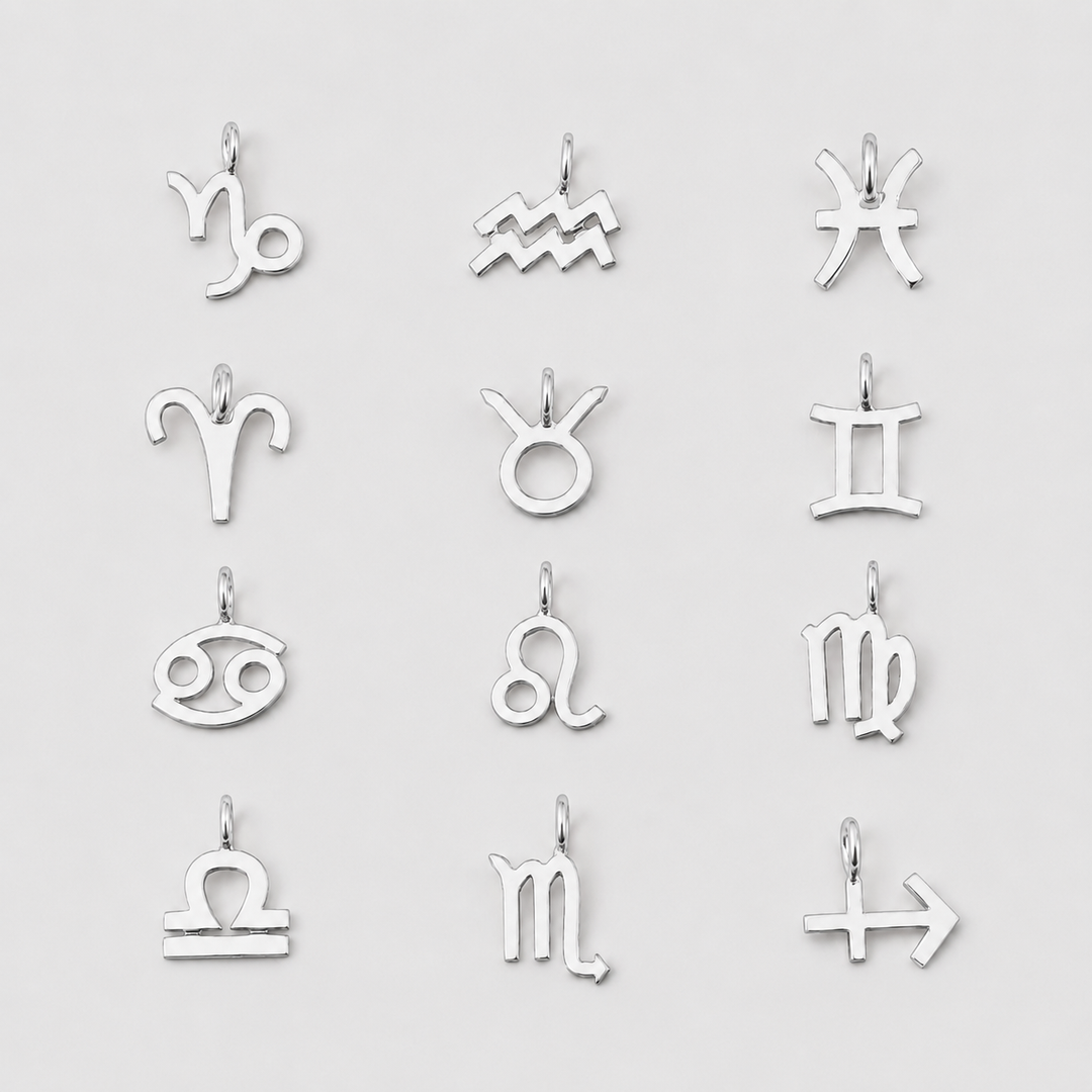 Set of silver zodiac charm pendants on a light gray background