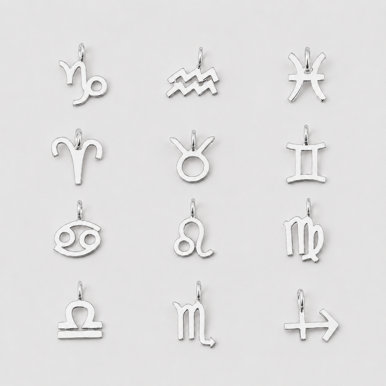 Set of silver zodiac charm pendants on a light gray background