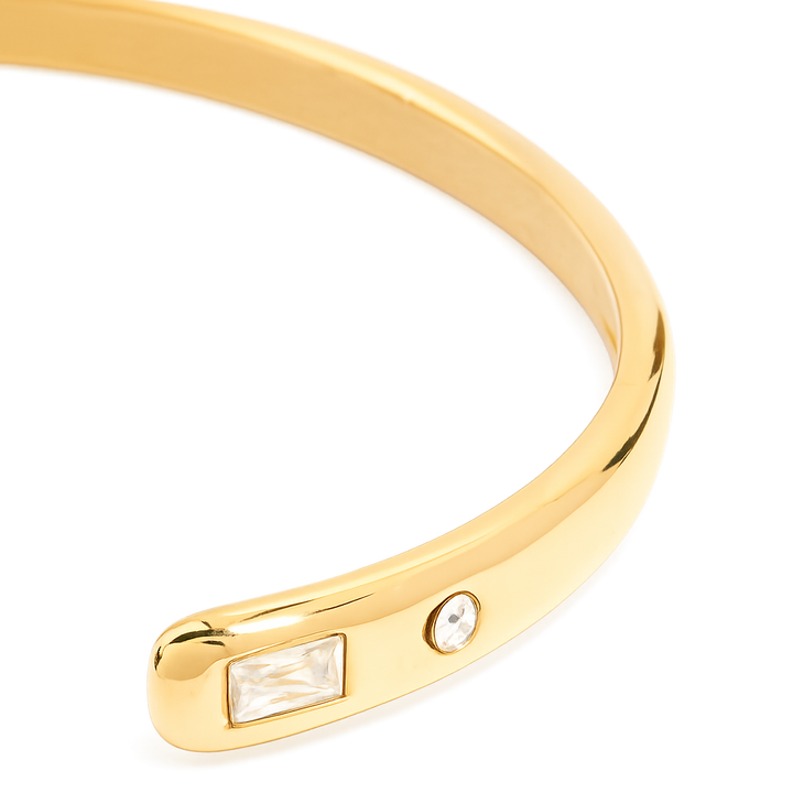 Gold bracelet with embedded gemstones on a white background
