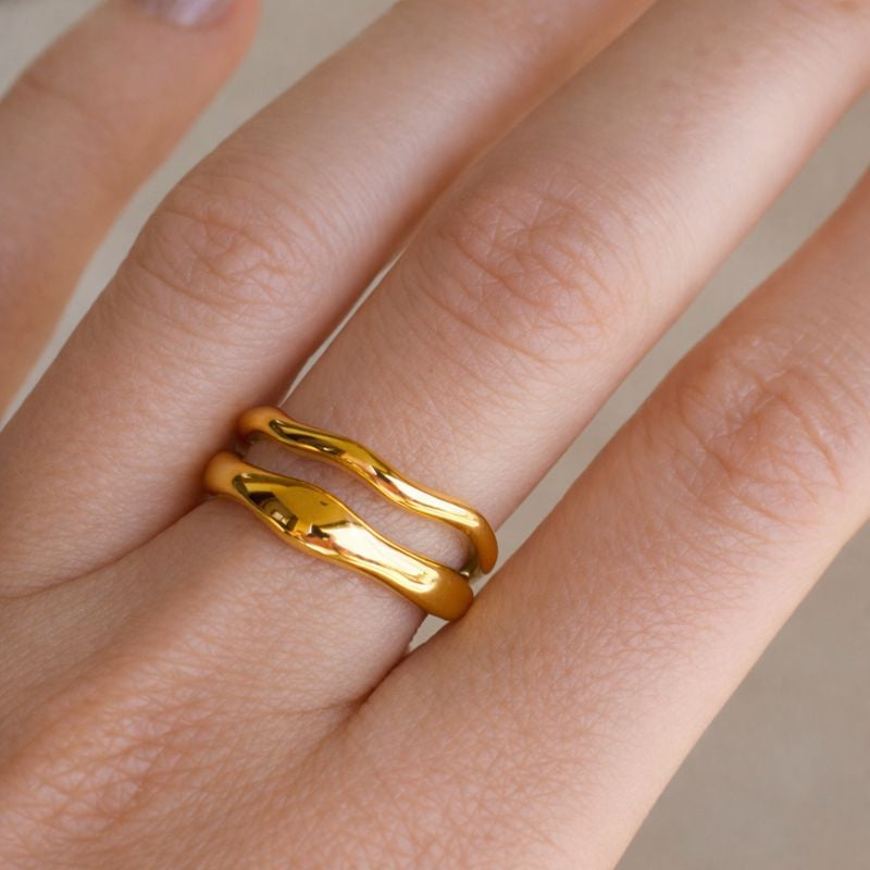 Gold ring on a person's finger with a neutral background