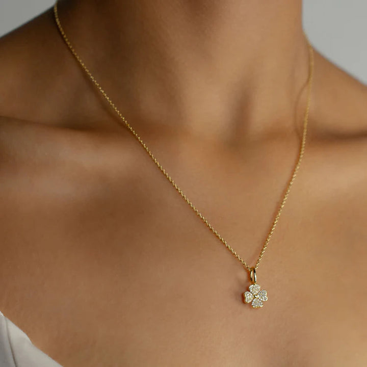 Gold necklace with a delicate pendant on a person's neck against a neutral background