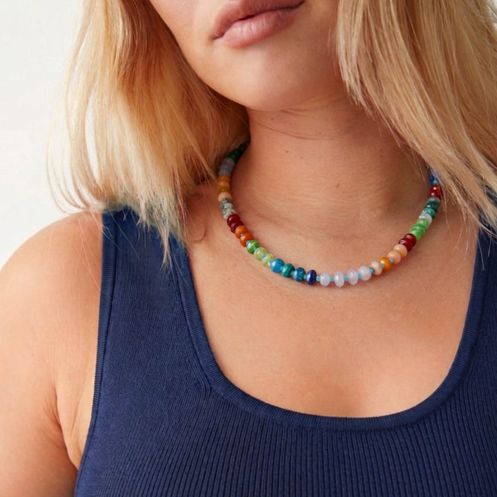 Close-up of a woman wearing a colorful beaded necklace with a plain background