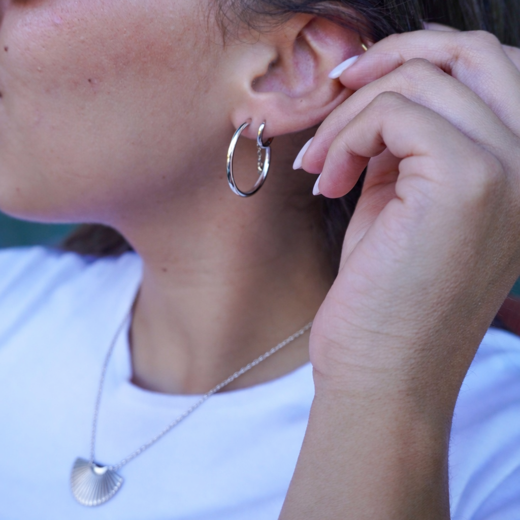 Person wearing a silver hoop earring with a blurred background