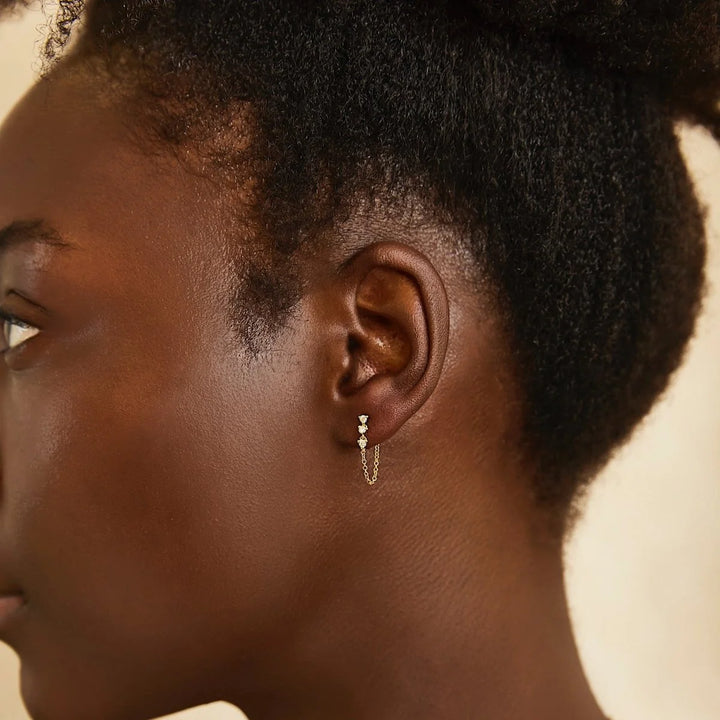 Close-up of a person wearing a delicate earring with a soft background