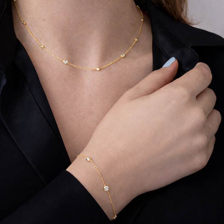 Gold necklace and bracelet on a person wearing a black outfit