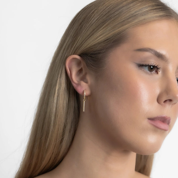 Close-up of a woman wearing a gold earring against a white background
